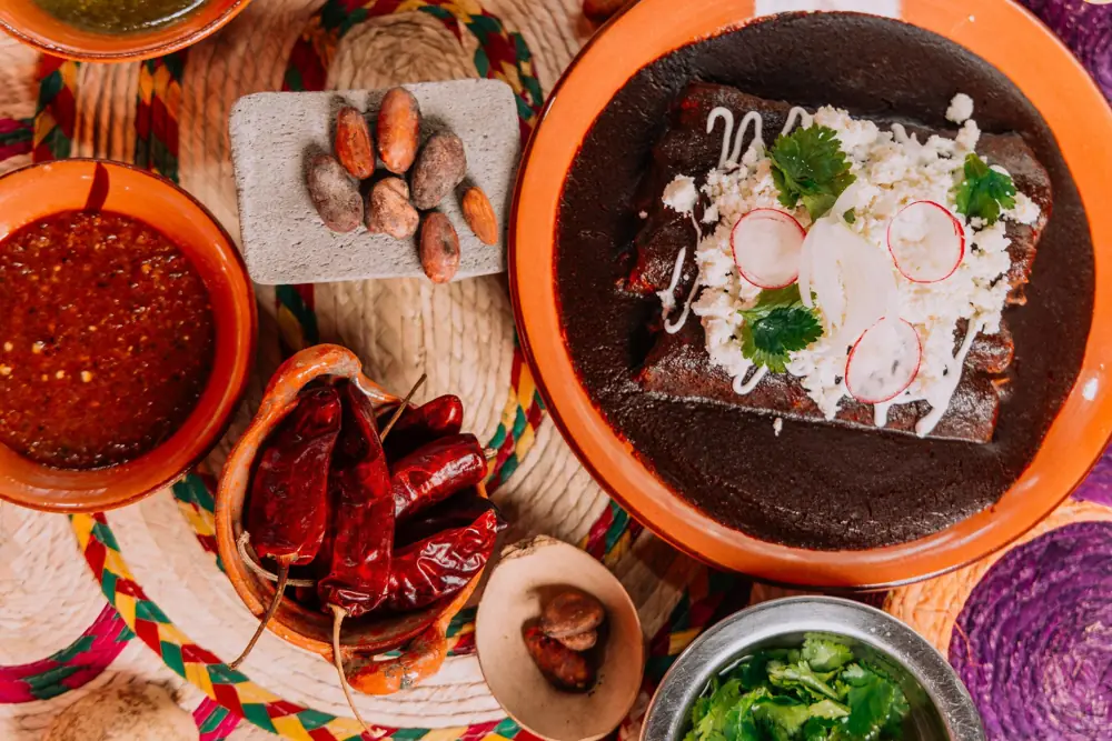 Enchiladas en mole negro junto a chiles secos, cacao y salsas